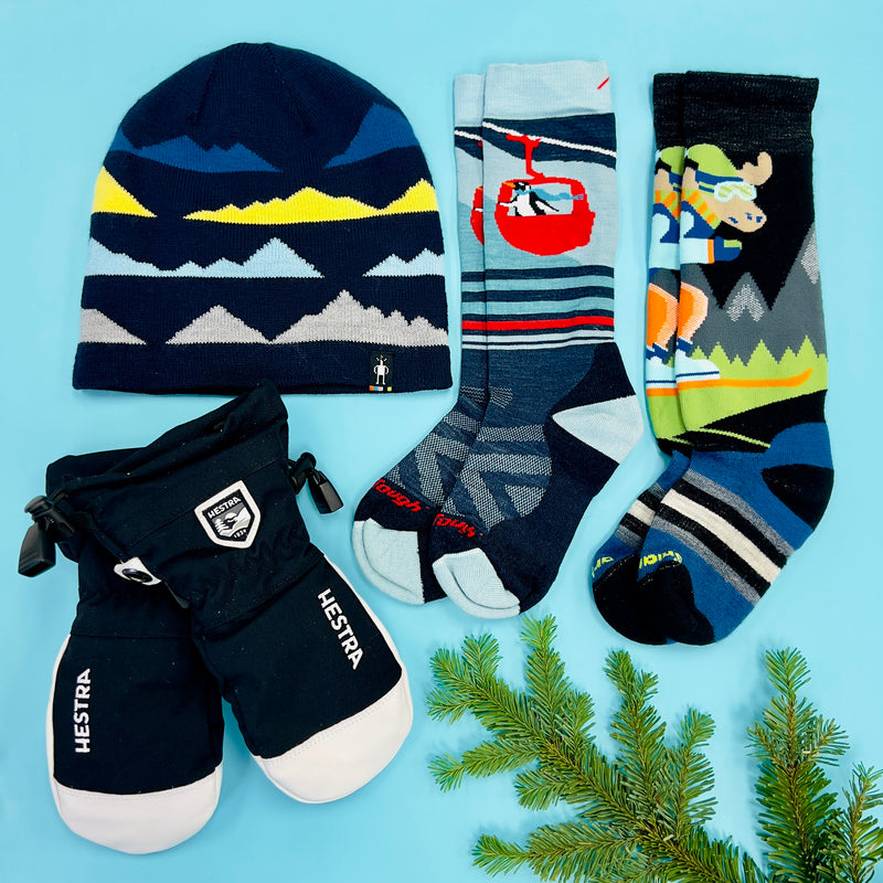 A flat lay of gifts for kids, including a pair couple socks, mittens,and a hat